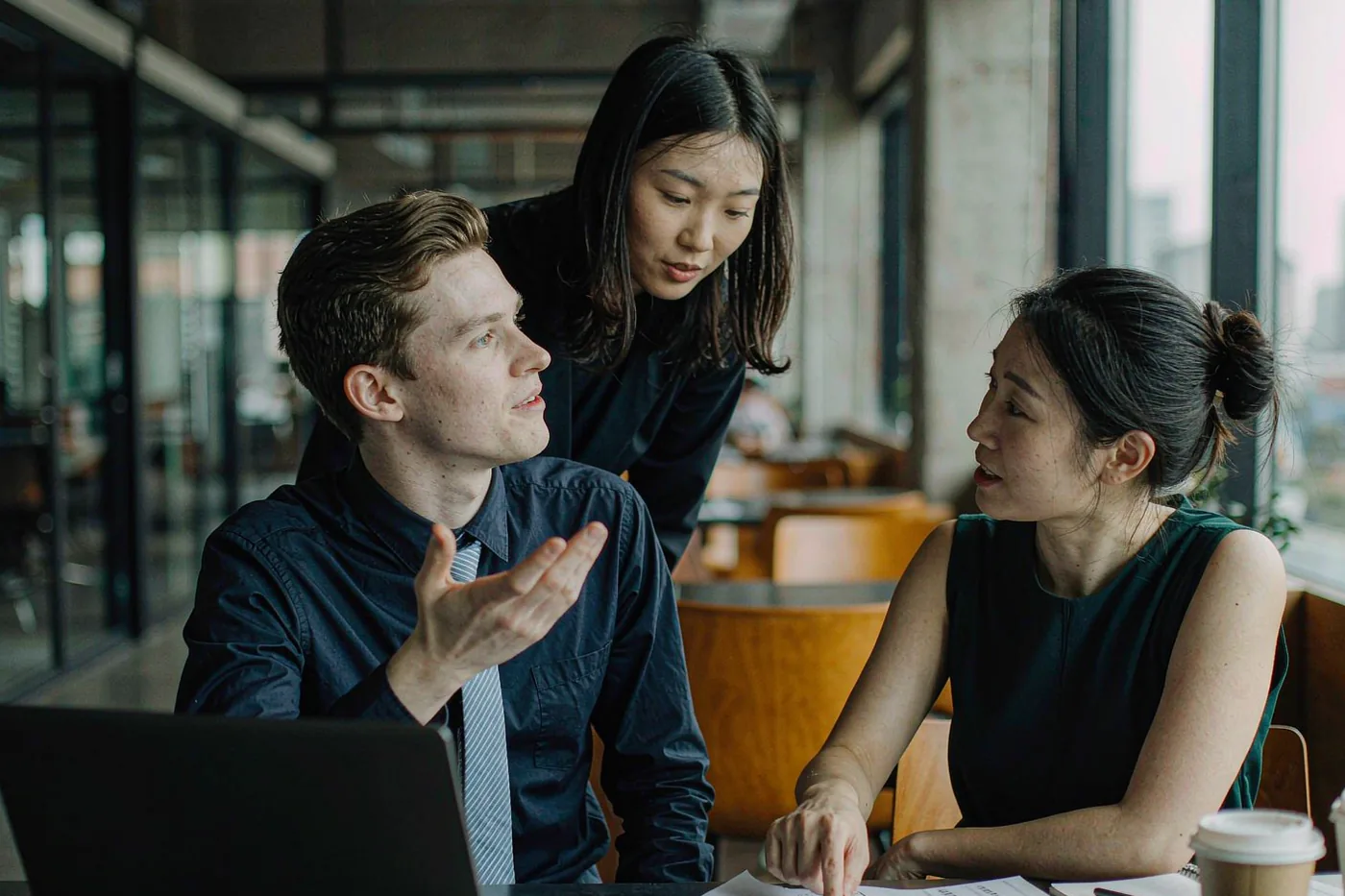 An international intern discussing work with Chinese colleagues in a modern office in China