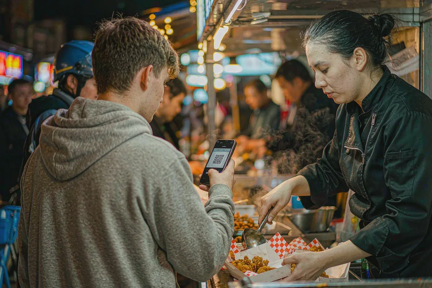 Foreign student paying with WeChat Pay at a Chinese night-market food stall