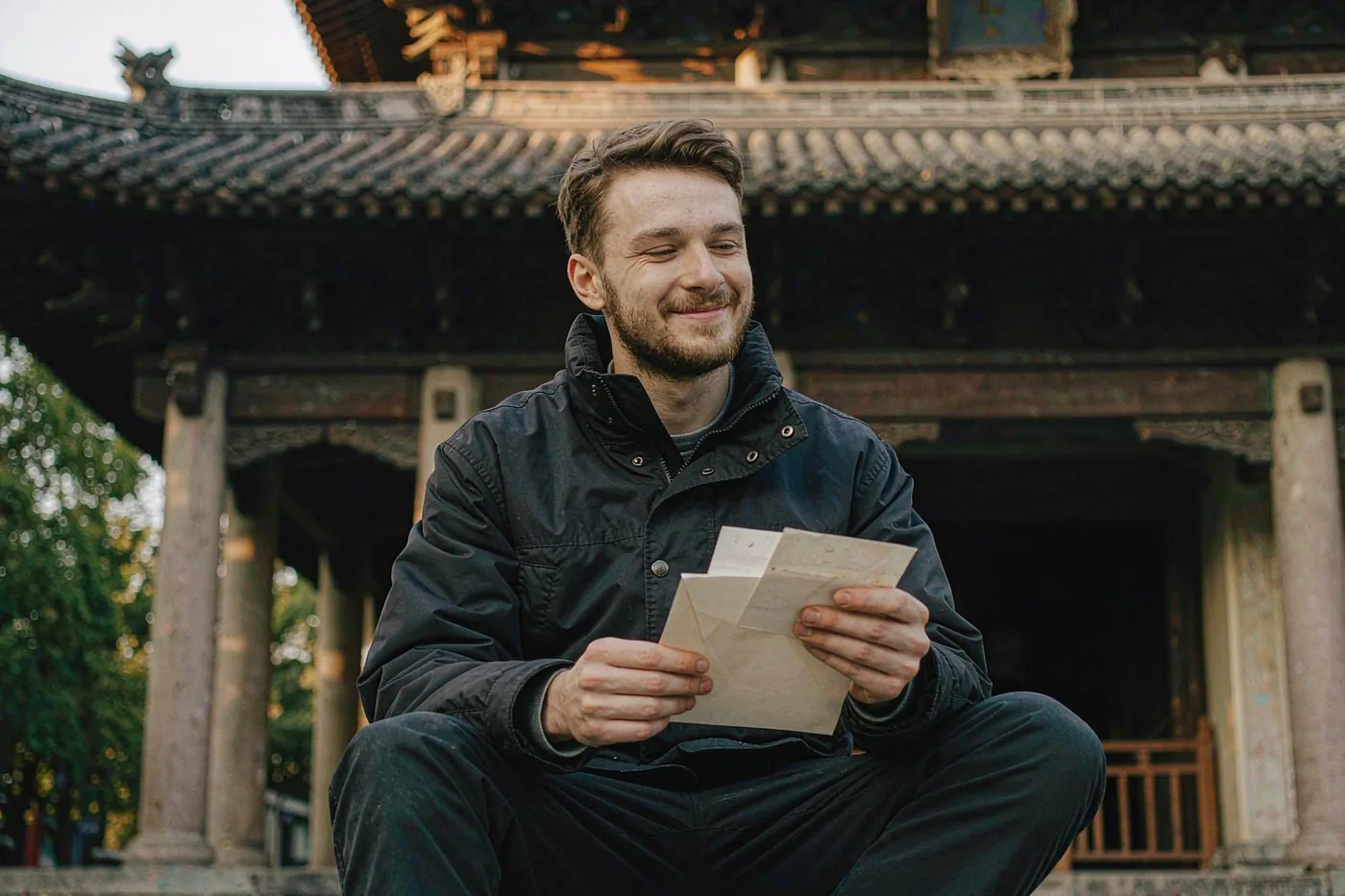 An international student reading a scholarship award letter outside a Chinese university building