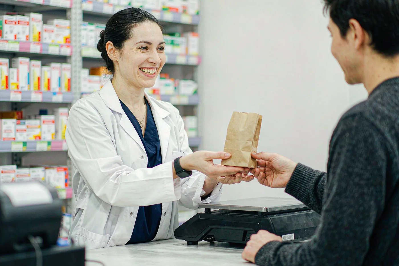 A pharmacist handing medicine to a customer across a pharmacy counter in China