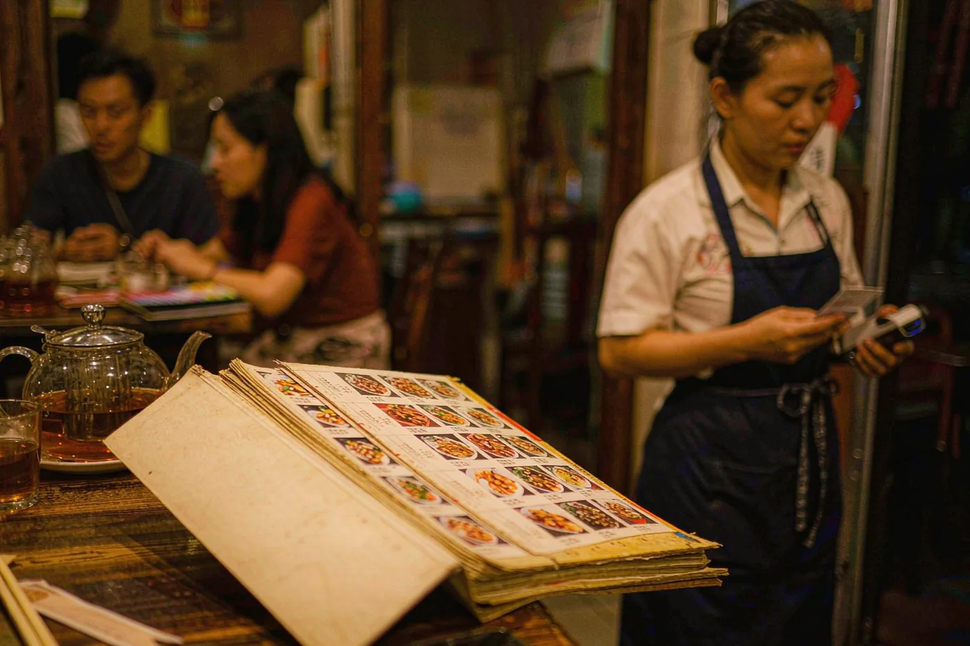 A Chinese restaurant menu and teapot on a table while ordering