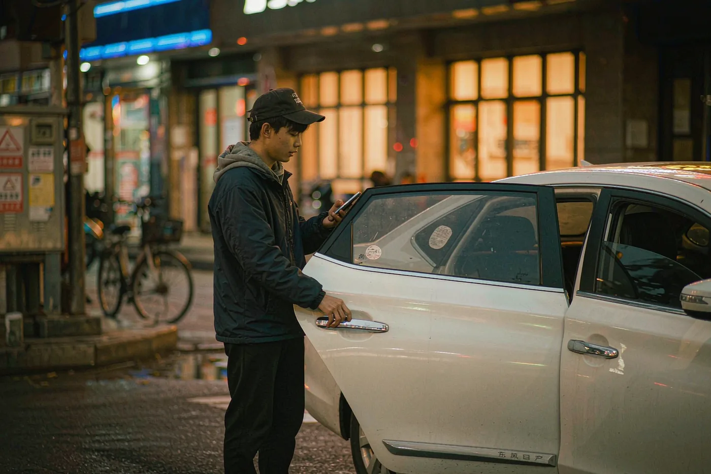 A passenger checking a ride-hailing car at the roadside in a Chinese city
