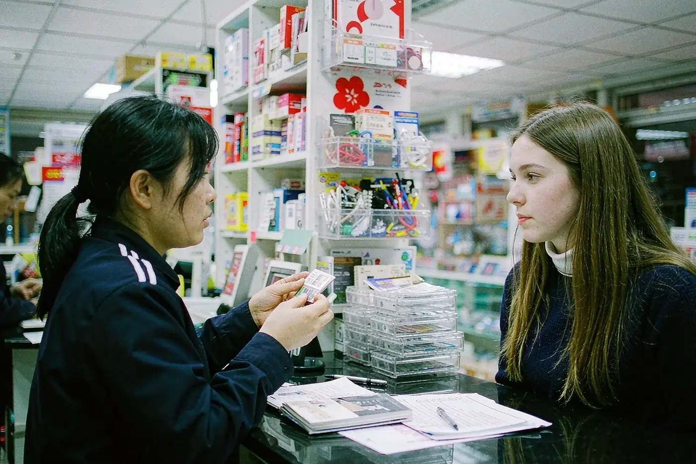 A staff member helping a foreign student register a SIM card at a Chinese mobile shop