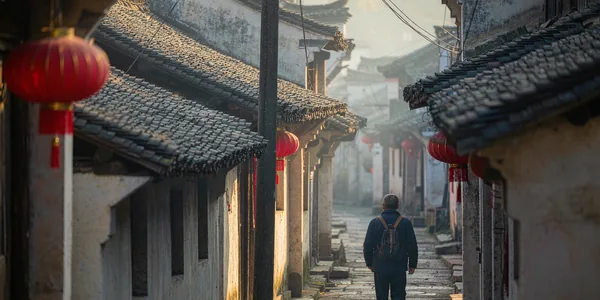 Traveler walking through a traditional Chinese old town alley with red lanterns